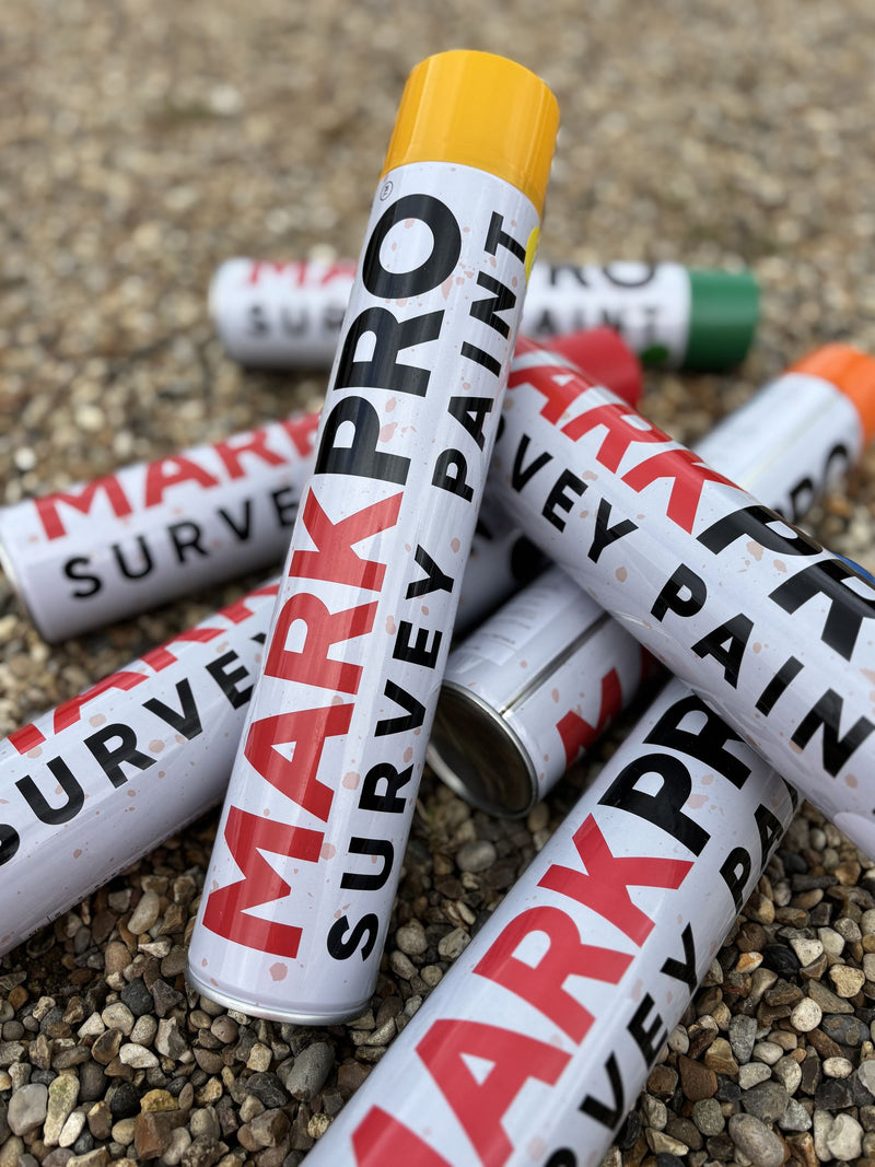 Several MarkPro Survey Paint cans on gravel, caps showing the colour range